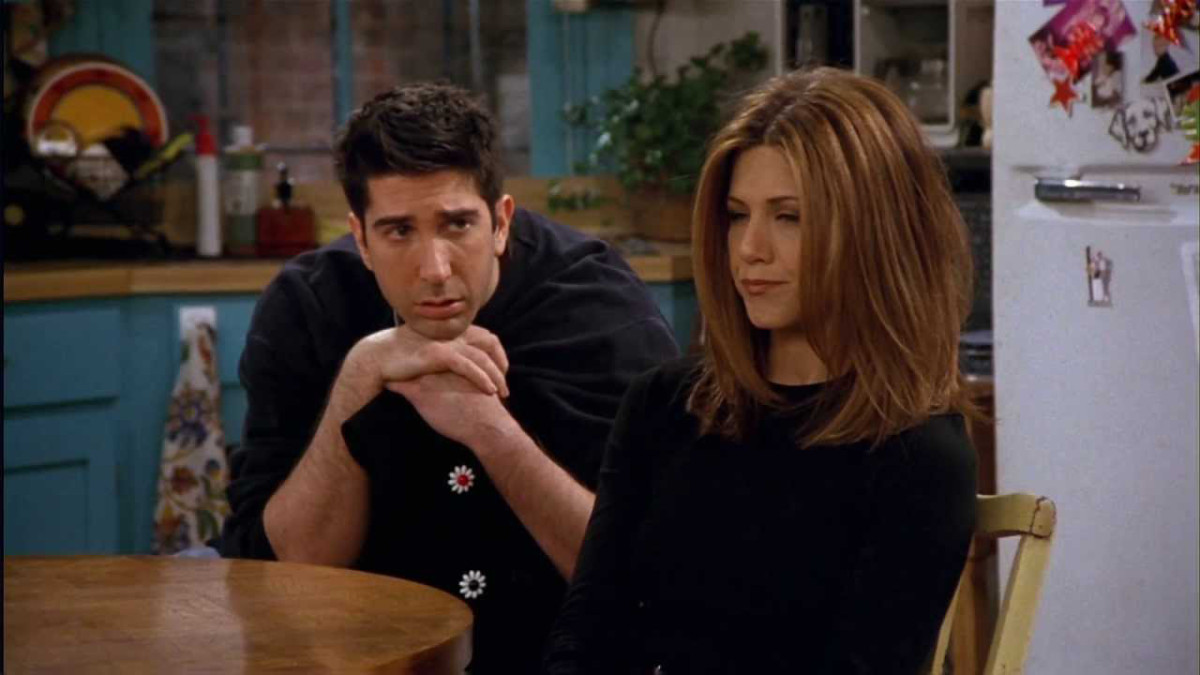 ross with his hands folded under his chin watching rachel who looks away.